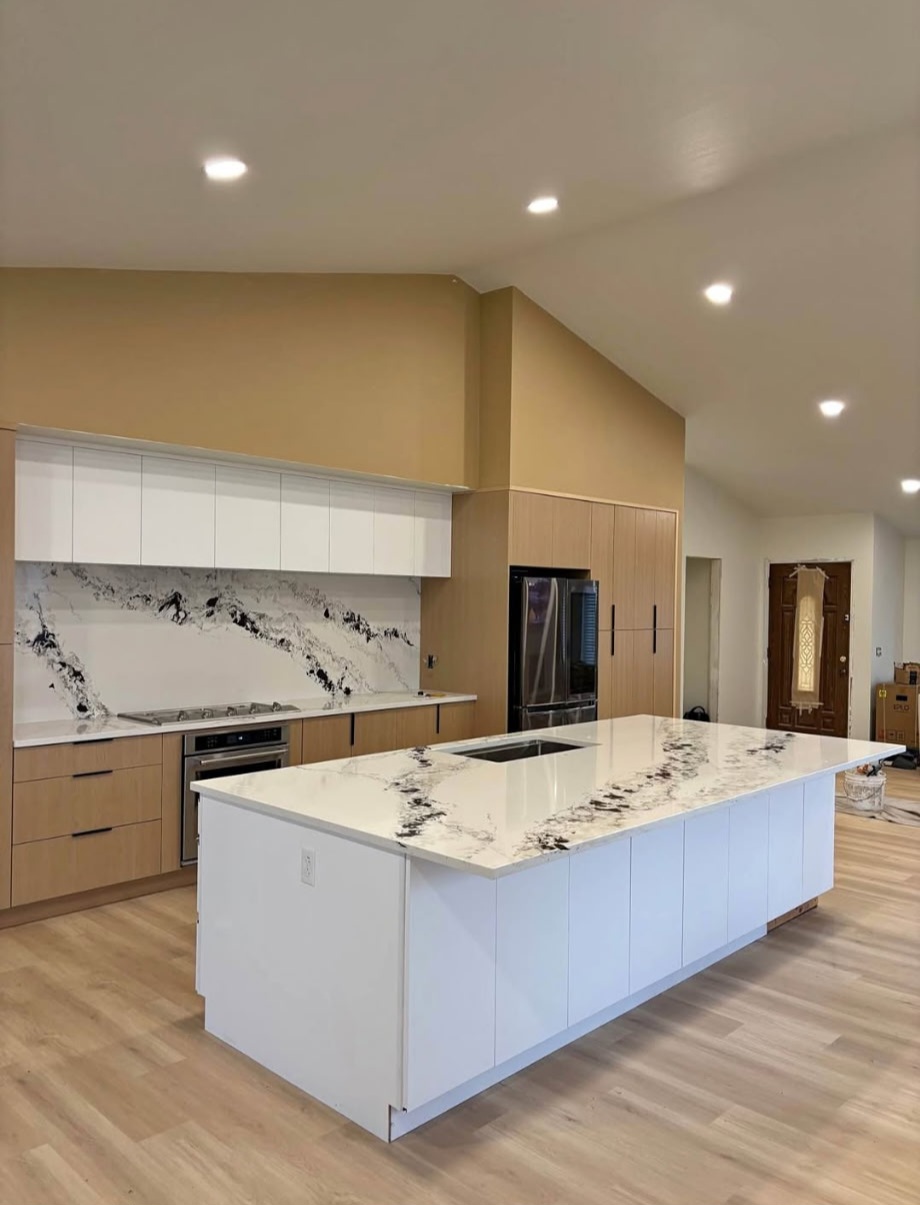 Large white quartz island with dramatic black veining and vaulted ceiling kitchen with light wood cabinets