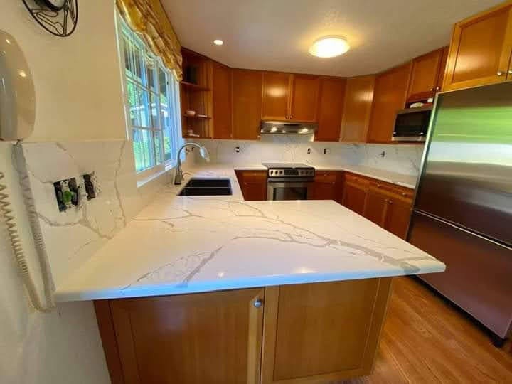 Calacatta quartz peninsula countertop with honey oak cabinets and stainless appliances