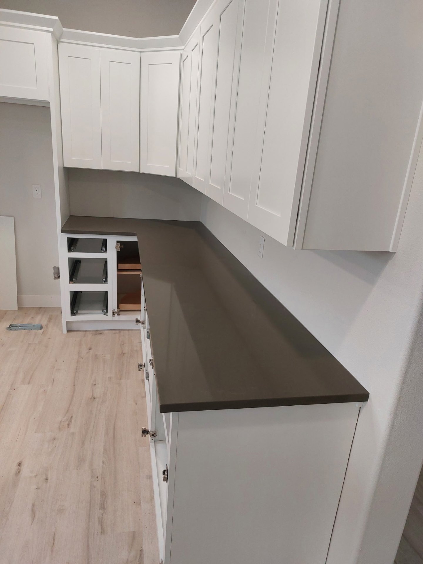 Dark gray quartz countertops with white shaker cabinets in an L-shaped kitchen