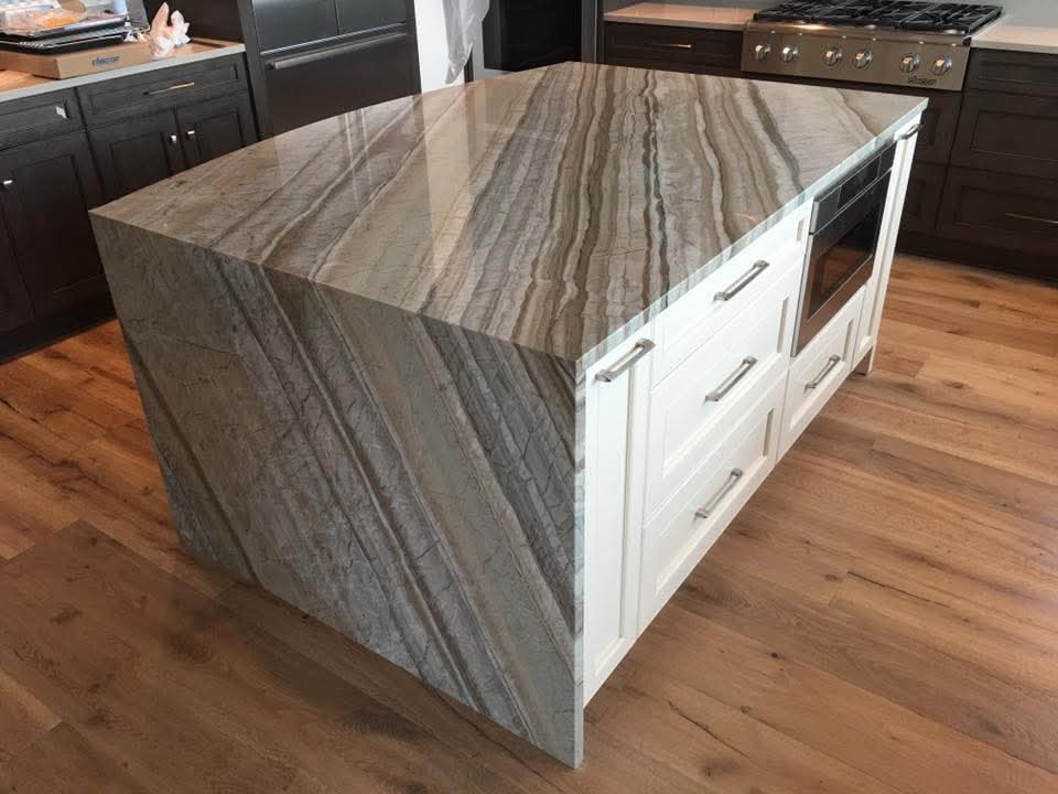 Brown and tan quartzite waterfall island with dramatic linear veining and white cabinets