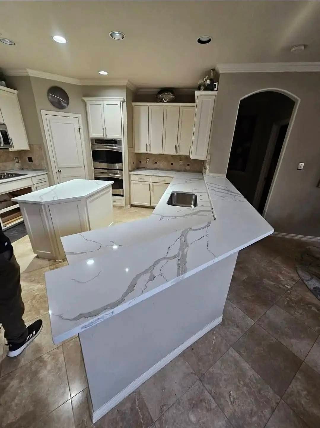 Calacatta quartz peninsula countertop with dramatic gray veining and cream shaker cabinets