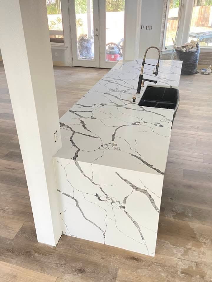 Calacatta quartz peninsula waterfall countertop with black undermount sink and gold faucet