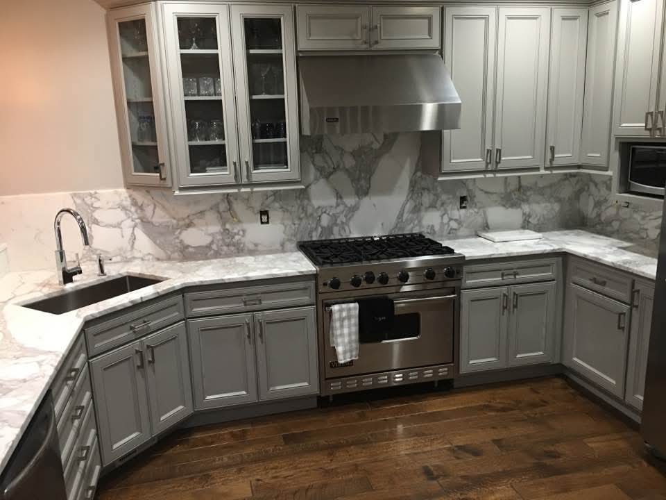 Calacatta marble kitchen with gray cabinets, Viking range and bookmatched slab backsplash