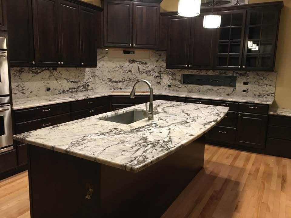 White and gray granite island and counters with dark espresso cabinets and matching slab backsplash