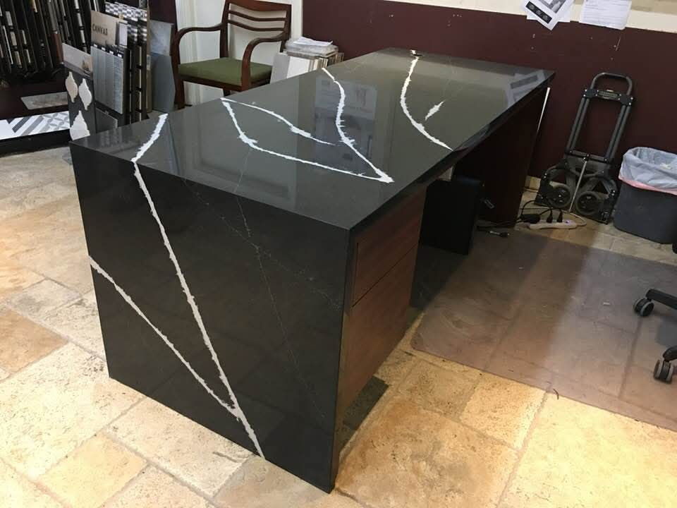 Black quartz showroom display island with bold white veining and waterfall sides